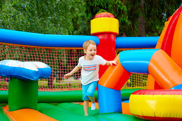 Wall Mural - happy excited boy having fun on inflatable attraction playground