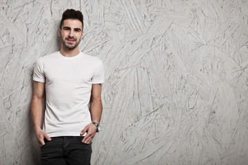 Smiling man in white blank t-shirt, and OSB wooden wall background