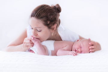 young mother and newborn baby in white bedroom