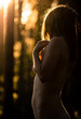 Nudes woman in the forest, summer sunny day and fusion with nature