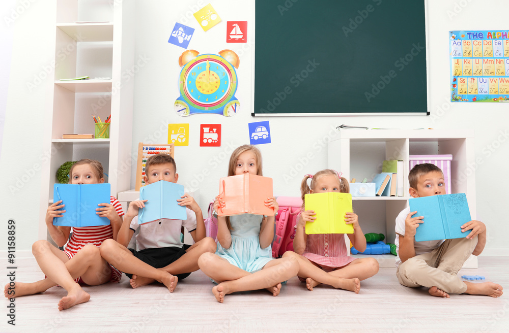 Row of children reading on floor in classroom