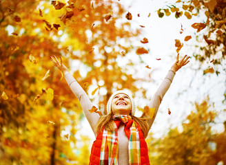 Wall Mural - Happy girl throws up autumn leaves in park for walk outdoors