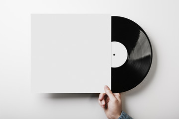 hand holding vinyl music album template on white wall background