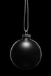 Hanging black Christmas ornament on a black background. Low key.