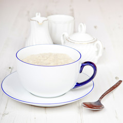 Porridge in breakfast cup on a white wooden table