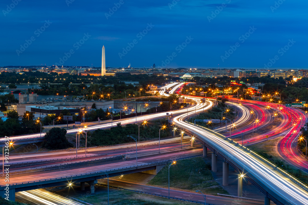 Washington D.C. cityscape at dusk with rush hour traffic trails on I-395 highway. Washington Monument, illuminated, dominates the skyline. - obrazy, fototapety, plakaty 