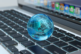 Fototapeta Do przedpokoju - Global computer network communication, internet business and marketing concept, blue transparent Earth globe on laptop keyboard macro view