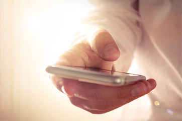 Wall Mural - man's hand holding and using a smartphone. concept for business and technology, for background, webs