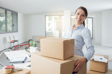 Happy woman carrying boxes into her new office