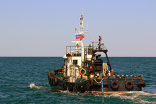 The Old Sea Tug With A Russian National Flag On The Mast Pulls The Tow Rope