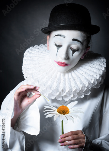 Naklejka na drzwi Sad mime Pierrot guessing on a daisy