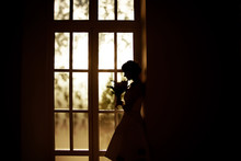 Bride With A Bouquet Of Standing At The Window
