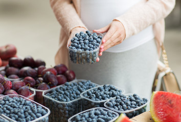 pregnant woman buying blueberries at street market