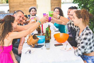 Group of people sitting having lunch together and toasting