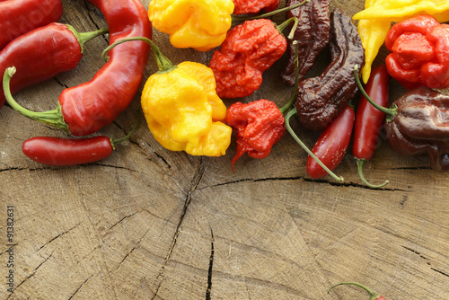 Naklejka na szybę Assorted mix of very hot peppers on a wooden background with space for content on bottom.