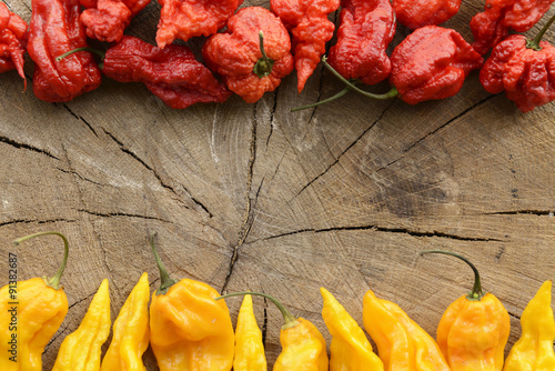 Naklejka na szybę Carolina reaper and fatalii extreme hot peppers on a wooden background arranged at the top and bottom with space for content.