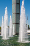 Fototapeta Tęcza - water spray in fountain near business buildings