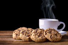 Steaming Cup Of Coffee With Chocolate Cookies On Wood