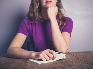 Thoughtful young woman writing in notepad