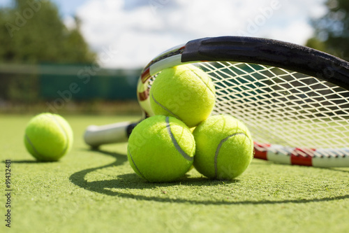 Cuadros en Lienzo Las pelotas de tenis y raqueta en la cancha de césped