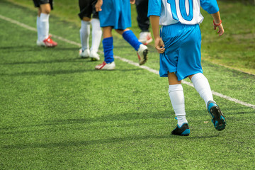 Wall Mural - Kids playing soccer on a pitch during football tournament