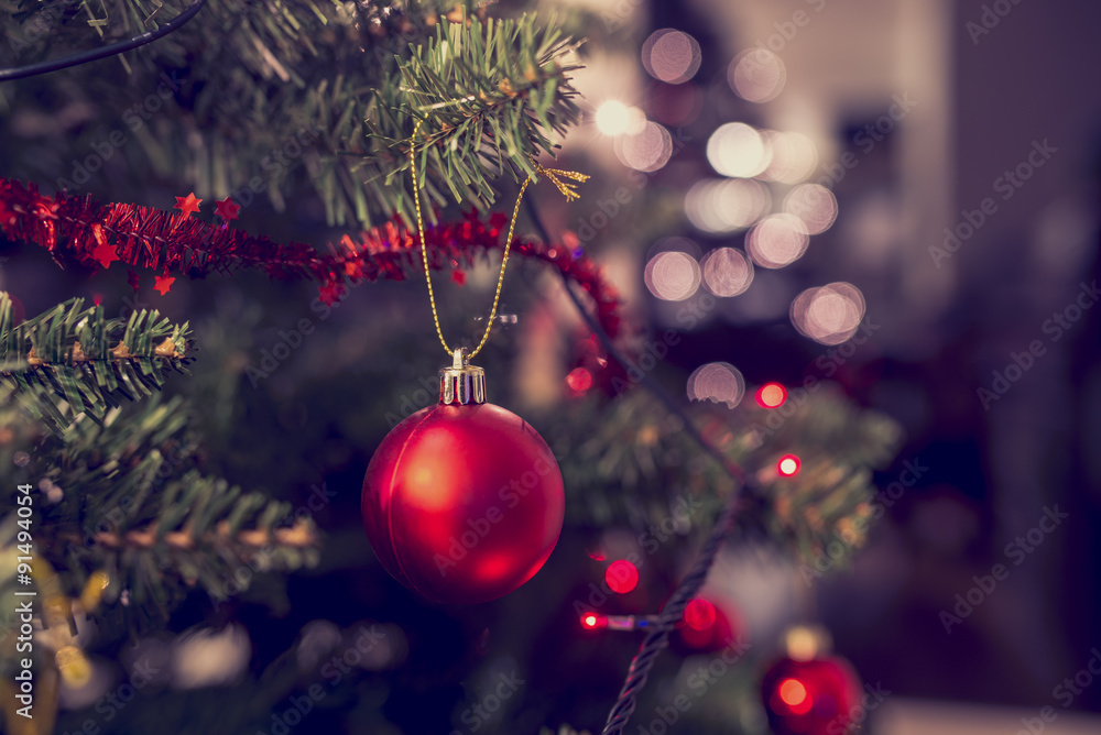 Closeup of red bauble hanging from Christmas tree - obrazy, fototapety, plakaty 