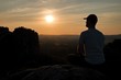 © rdonar - Man with baseball cap on top of mountain. Silhouette of rocks.