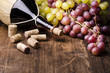 fiasco di vino con uva e turaccioli su tavola di legno