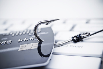 Wall Mural - credit card phishing - piles of credit cards with a fish hook on computer keyboard
