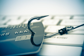 Wall Mural - credit card phishing - piles of credit cards with a fish hook on computer keyboard