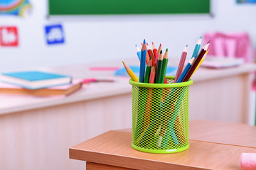 Desktop with cup of crayons in classroom