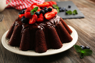 Wall Mural - Delicious chocolate cake with berries in plate on table, closeup