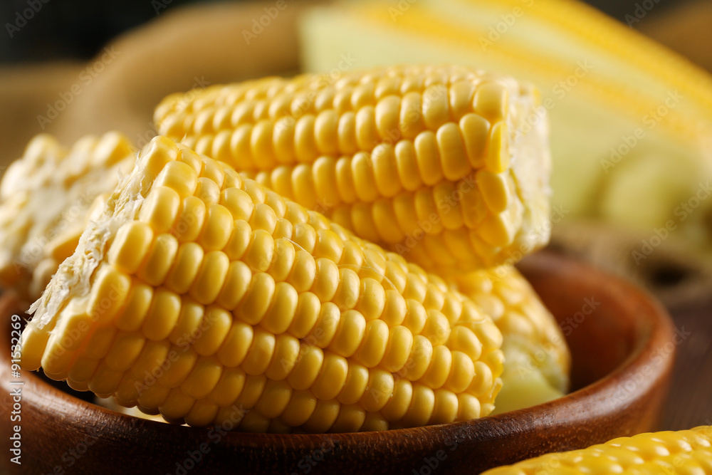 Ripe corn in bowl on wooden background