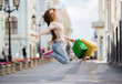 Happy beautiful woman with colorful shopping bags in hand cheerfully jumping in the air.
