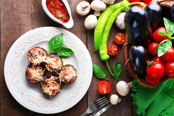 Poster - Dish of eggplant with cherry tomatoes and cheese in white plate on wooden table, top view