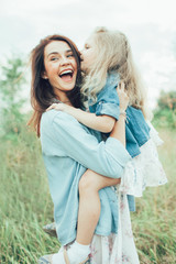 The young mother and daughter on green grass background 