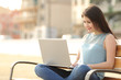 © Antonioguillem - Student girl browsing a laptop sitting in a bench