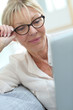 © goodluz - Senior woman with eyeglasses connected on digital tablet