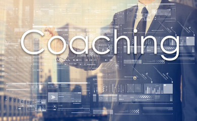 businessman writes on board text: Coaching - with sunset over th