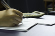 © suradech_k - A woman notes and calculates number on the note card with calculator in background