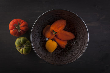 Different red and green bell peppers on a rustic wooden table