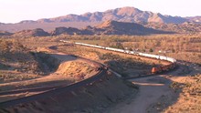 A Freight Train Moves Across The Desert From A High Angle.
