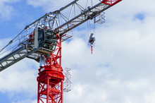 Red Construction Tower Crane With Grey Jib And Hook Isolated On Blue Sky With White Clouds Background, Detail 