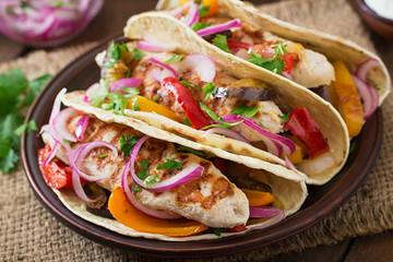 Mexican tacos with chicken, grilled vegetables and red onion.