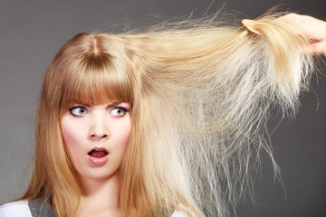 Blonde woman with her damaged dry hair.