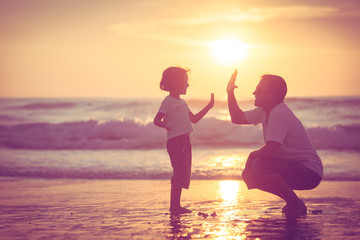 Sticker - Father and son playing on the beach at the sunset time.