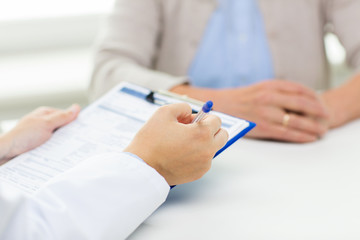 Canvas Print - close up of senior woman and doctor with clipboard