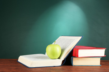 Sticker - Open books and green apple on desk on green chalkboard background