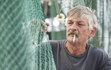 Wall Mural - fisherman mending nets