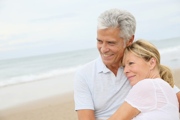 Wall Mural - In love senior couple embracing at the beach